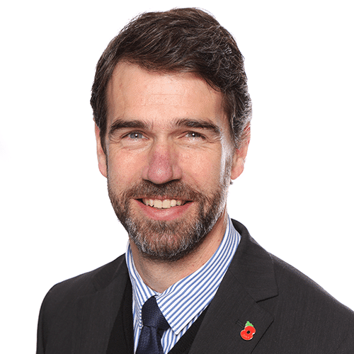 A smiling man in a suite with a poppy pin badge (Ben Riggott Embark Federation)